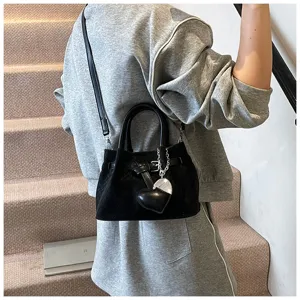 Close-up detail of black woven crossbody bucket bag with elegant belt buckle and heart charm.