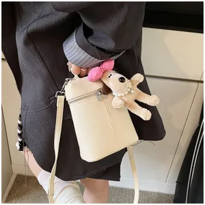Detail view of the mini bucket crossbody bag featuring a cute plush dog charm and chic style.