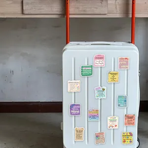 Detailed view of various motivational quote stickers displayed on a clean white suitcase.