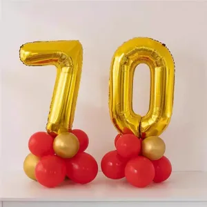 Gold number 70 foil balloons set with red latex balloon bases for milestone birthday party decor.