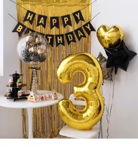Birthday party scene decoration detail showing gold number balloons, banner, and festive setup.