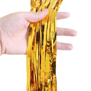 Gold foil fringe curtain detail shot, shiny metallic tinsel backdrop for party stage decoration.