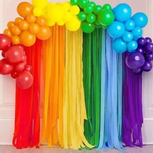 Colorful crepe paper streamers backdrop decoration with rainbow balloon arch for party events.