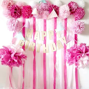 Pink crepe paper streamer backdrop and pom poms for birthday party wall decoration details.