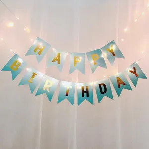 Detail view of blue gold Happy Birthday banner with fairy lights for party decoration setup.