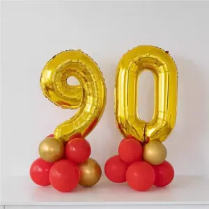 Gold number 90 foil balloons with red latex balloon base for birthday party decor.