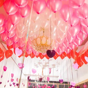 Detailed view of pink and red balloon party ceiling decoration with hanging hearts setup.
