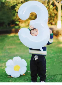 Detailed view of the white number 3 foil balloon in an outdoor party decoration setting.
