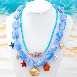 Detalle de collar de cuentas de doble capa estilo playa con dijes de estrella de mar y concha.