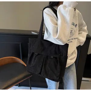 Black corduroy tote bag with multiple front pockets, stylish casual shoulder bag for women.