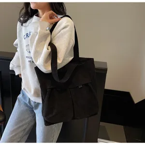 Black corduroy tote bag detail showing multiple functional pockets and spacious design.