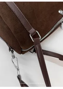 Bolso de hombro cilíndrico de ante marrón detalle de herrajes estilo retro y textura.