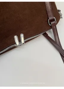 Primer plano detallado del bolso tote retro de ante marrón con cremallera y correa.