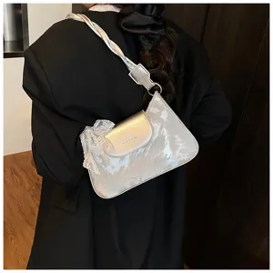 Vue détaillée du sac porté épaule argenté avec fine bordure en dentelle et poignée tressée.