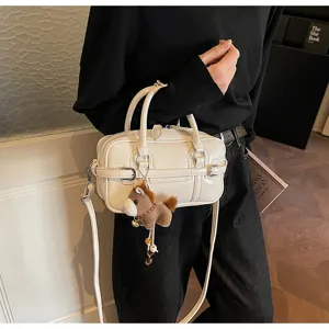 Detail view of the stylish cream handbag with cute pony pendant, premium leather and fine stitching.