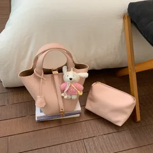 Pink leather bucket bag detail view with cute bunny keychain and matching cosmetic pouch.