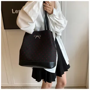 Vista dettagliata della elegante borsa nera con motivo a cuori rossi e fiocco argento.