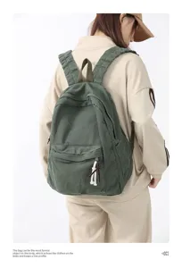 Vue détaillée du sac à dos en toile vert foncé, mettant en valeur la poche avant et les détails.
