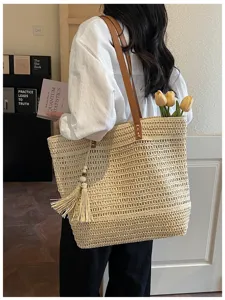 Primo piano della borsa di paglia intrecciata con manico in pelle e nappa per vacanze estive.