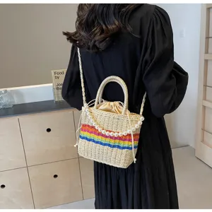 Detail shot showing a straw woven bucket bag with colorful rainbow stripes and pearl strap.