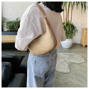 Detailed shot of a stylish straw woven hobo shoulder bag with PU leather strap, worn by model.
