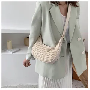 Close-up of stylish straw woven underarm shoulder bag detail showing texture and design.