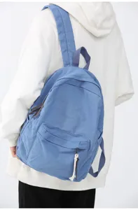 Vue détaillée d'un sac à dos en toile bleue porté au dos, avec des bretelles solides et design.