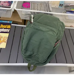 Vue détaillée du sac à dos en toile vert foncé au style décontracté avec une matière résistante.