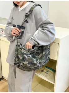 Close-up of casual camo canvas crossbody bag worn by model, showing soft slouchy texture detail.