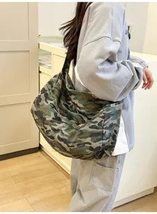 Detail shot of a casual camo canvas cross-body bag, showcasing large capacity and durable strap.