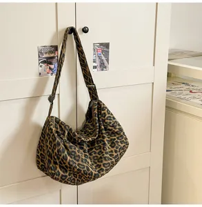 Detailed view of a trendy leopard print canvas shoulder bag hanging on a minimalist cabinet.
