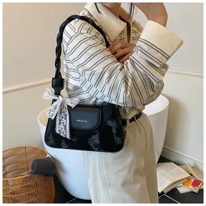 Vue détaillée du sac porté épaule noir élégant avec poignée tressée et nœud en dentelle.