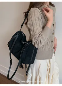 Bolso de hombro de ante negro, detalle minimalista elegante con cremallera metálica y candado.