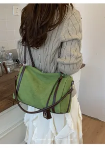 Bolso de hombro retro de ante verde con correas de cuero marrón y detalle de candado.