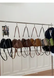 Vista detallada de bolsos de hombro retro de ante colgando en una barra elegante.