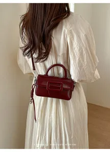 Detail shot of the vintage burgundy crossbody bag featuring a chic buckle flap design.
