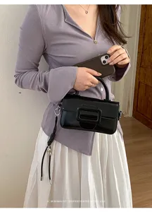 Chic black patent leather mini square handbag detail, elegant retro style crossbody bag.