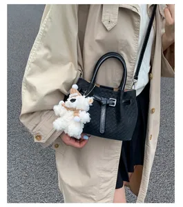 Detailed view showing the black vintage woven bucket bag with stylish belt and cute bear charm.