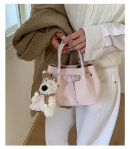 Detail view of a pink PU leather bucket bag with a cute fluffy bear pendant and belt buckle.