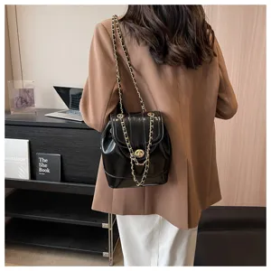 Gros plan détaillé du sac à dos élégant en cuir vernis noir avec de luxueuses chaînes dorées.