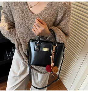 Close-up view of a stylish black PU leather bucket handbag with gold plaque and chic charms.