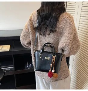 Detailed view of the trendy black PU leather bucket bag with cute furry charms and hardware.