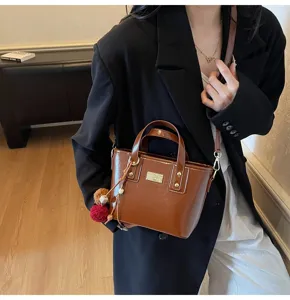 Stylish brown patent leather bucket bag for women, chic crossbody tote with metal charm.