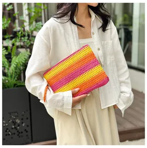 Gekleurde geweven stro-clutch tas met roze, gele en oranje strepen voor de zomer.