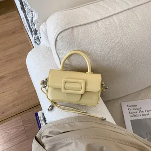 Detailed view of the trendy yellow mini handbag, highlighting the stylish front buckle and texture.