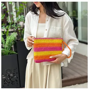 Gedetailleerd overzicht van de kleurrijke geweven strooien clutch met textuur en polsbandje.