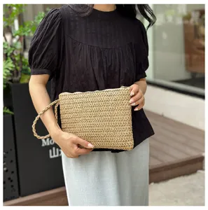 Geweven stro clutch tas detail met natuurlijke textuur, stijlvolle polsband en zomerdesign.