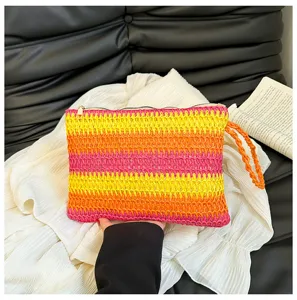 Gedetailleerd opname van een kleurrijk gestreepte gevlochten strooien clutch met polsbandje.