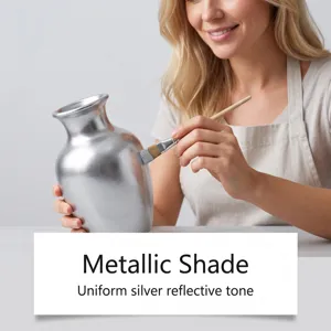 Detail view of applying metallic silver paint onto a ceramic vase with a brush, shiny shade.