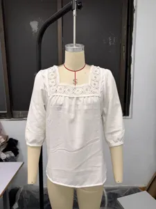 Detail view of white cotton linen women blouse, square lace patchwork neck, 3/4 sleeve design.